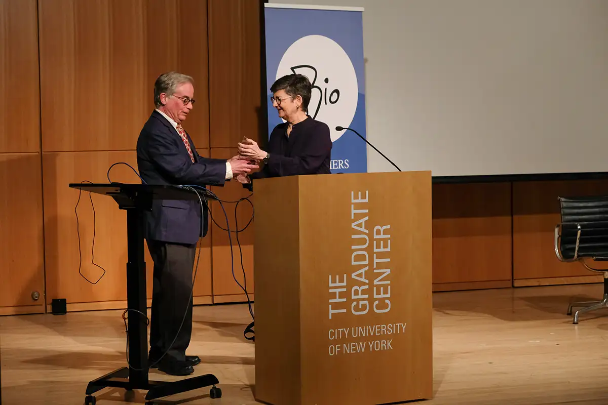 lady standing behind a podium handing an award to a man
