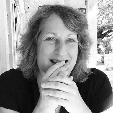Black-and-white portrait of smiling woman with chin resting on clasped hands