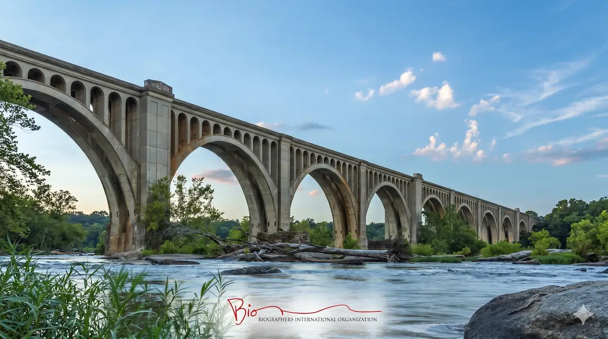 A long stone arch bridge crosses a river under a blue sky; text at the bottom reads "Bio BIOGRAPHERS INTERNATIONAL ORGANIZATION".